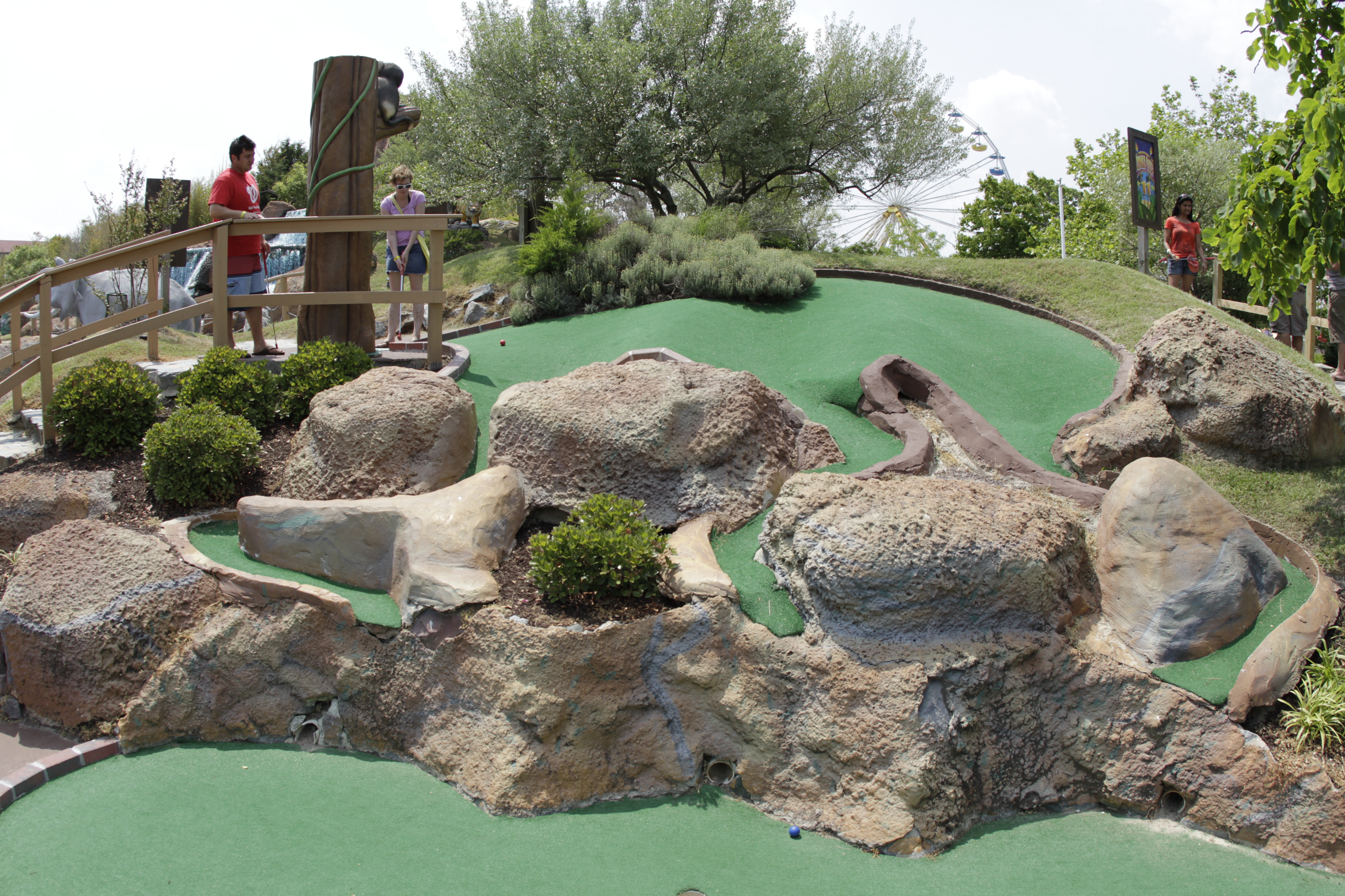jolly-rogers-green-mini-golf green turf grass on a miniature golf course with boulders and rope walk