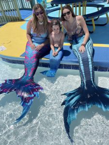 Mermaids posing with a little boy with a mermaid tail